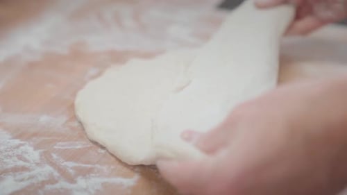 Nahaufnahme der Hände eines Bäckers, der Teig in Brotbackform faltet