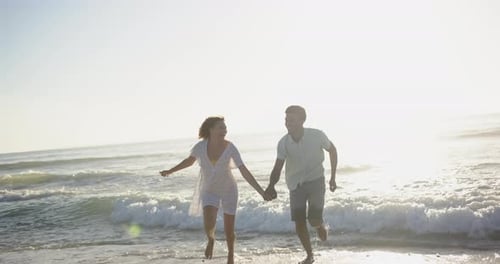 Biracial couple enjoys a playful run along the beach at sunset