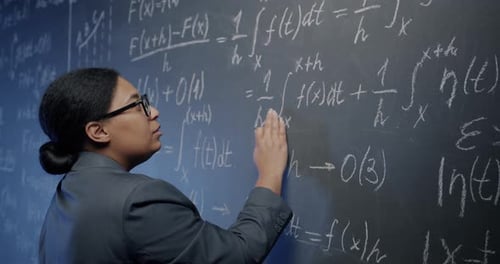 Adult Writes Math Equations on Chalkboard