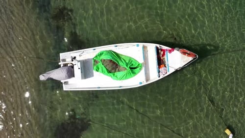 Small Fishing Boat anchored in a shallow lagoon, with packed Fish net onboard