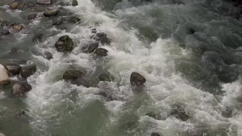 Fast flowing water rapids cascading down a rocky river. Still shot.