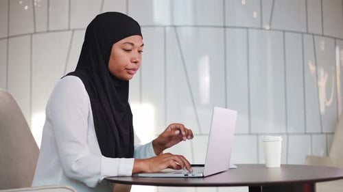 Woman Working on Laptop, Rubbing Temples in Office