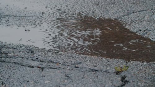 Starke Regentropfen fallen in eine Pfütze und überfluten die Straßen