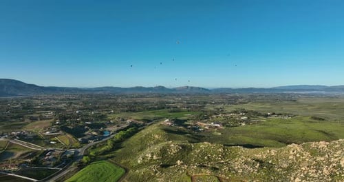 Aerial View Over Rolling Hills with Hot Air Balloons