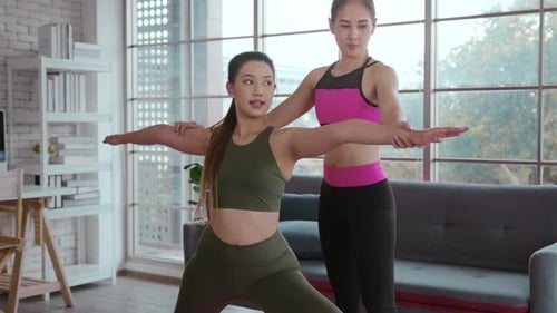 Women Practice Yoga Pose with Trainer