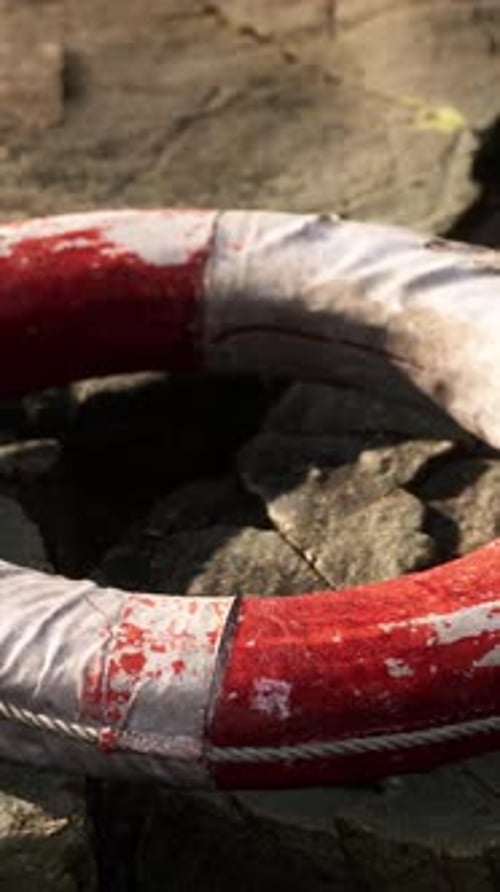 Weathered Red and White Lifebuoy on Coastal Rocks