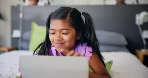 Girl with Tablet Smiling on Bed at Home