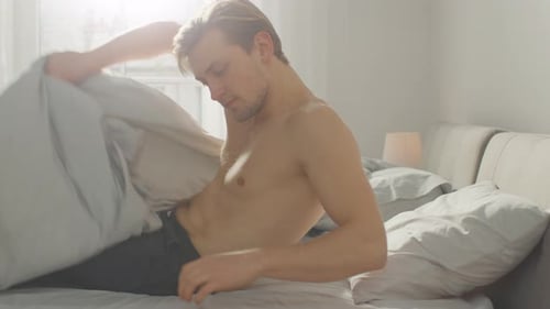 Man Wakes Up and Stretches in Bed