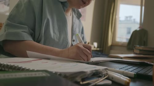 Young Adult Student Studying at Desk with Papers