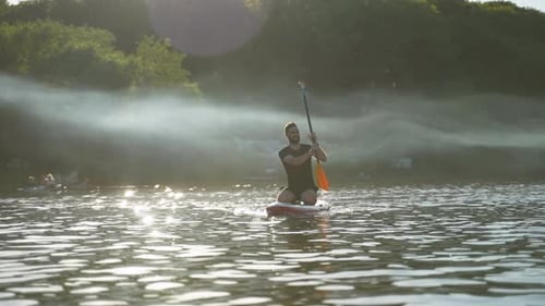 Sportsman Kneeling on Sup Board Paddling on Calm Lake at Sunset