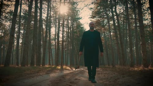 Axe Killer Man Walks Through Trees in Misty Forest to Find Victims