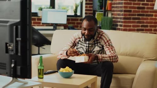 Man Eats Takeout Food on Couch at Home