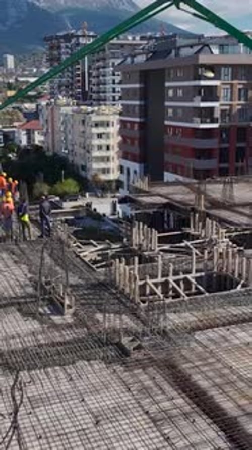 Vertical Video Workers Pour Concrete for a Multistory Residential Building on a Busy Construction