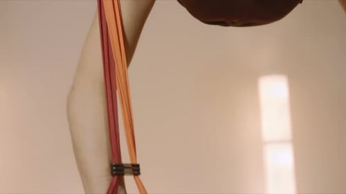 Smiling sporty girl doing splits in air in hammock during fly yoga workout at studio