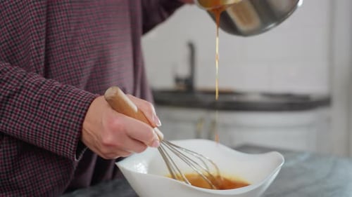 CloseUp of Cook Pouring Hot Liquid Into Bowl While Stirring Egg Mixture