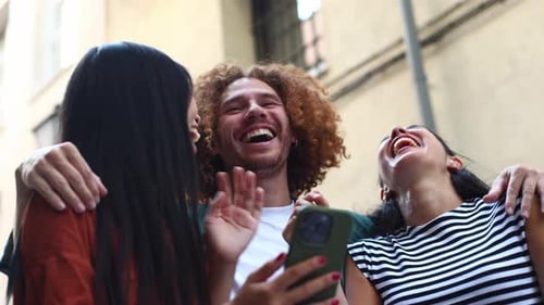 Three Friends Laughing and Looking at Phone Together