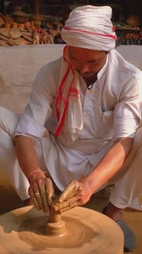 Potier lançant le tour de potier et façonnant un pot en argile dans un atelier de poterie en Inde
