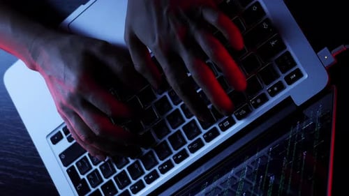 Person working on laptop computer keyboard with graphic user interface