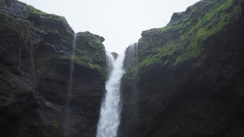 A waterfall in Iceland, surrounded by tall cliffs - Slow motion