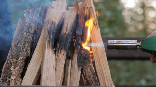 Flames Ignite Firewood with Blowtorch Outdoors