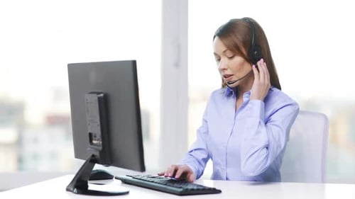 Busy asian helpline operator works at computer in modern office
