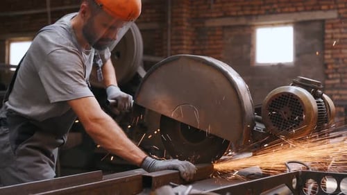 worker cuts metal on a circle and a circular saw. steel pipes and cylindrical blanks for welding.