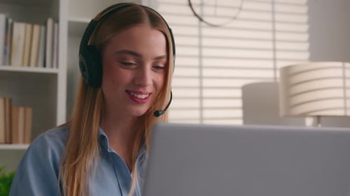 Smiling Woman with Headset Working on Laptop