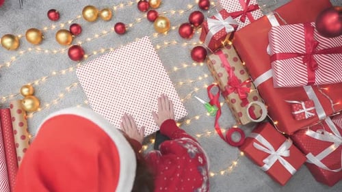 Woman wrapping christmas gifts with lights and ornaments