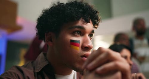 Man watching sporting event with face painted flag