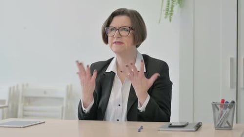 Businesswoman Talking at Desk in Bright Office