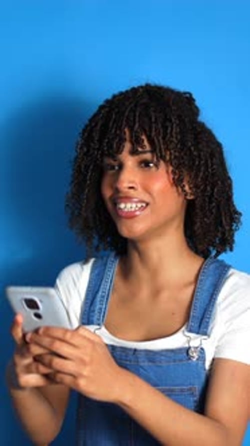 Young woman using smartphone on blue background