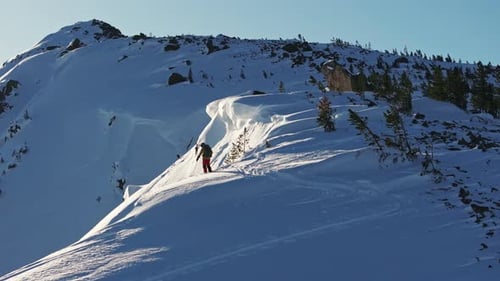 Bergsteiger besteigt den verschneiten Bergrücken bei Sonnenaufgang