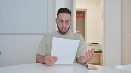 Man Reads Paper with Confused and Upset Expression