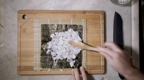Adult Spreading Sushi Rice onto Nori Sheet