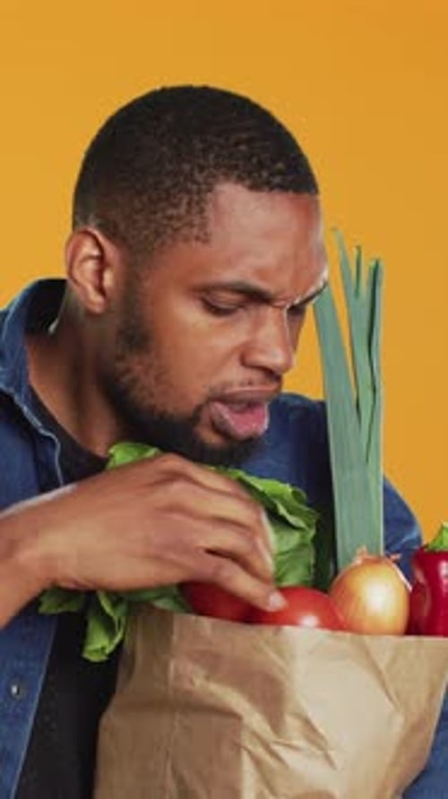 Young Adult Inspects Bag of Fresh Vegetables
