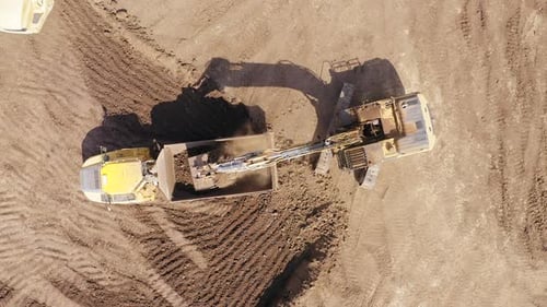 Excavator loading soil onto a Truck, Aerial view.