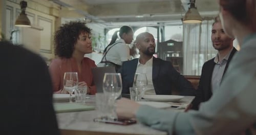 Group of Businesspeople having a Meeting in a Restaurant, using Laptop