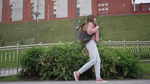 Female Student Confidently Walking on Campus Sidewalk Carrying Backpack While Heading Toward
