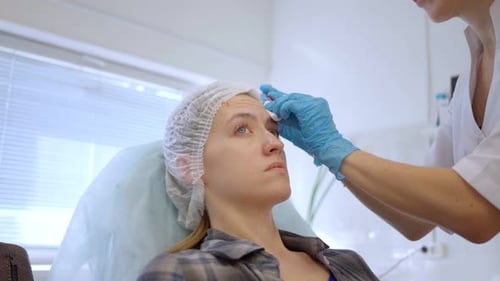 Professional Cleans Woman's Forehead in Clinic