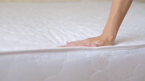 Close Up of a Girl's Hand Checks the Rigidity of a New Comfortable Orthopedic White Mattress for the