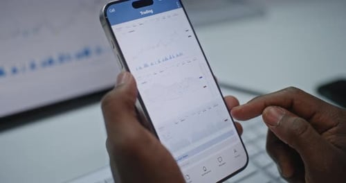 Close Up of Stock Exchange Trader Monitoring RealTime Stocks on Smartphone and Tablet Computer