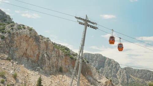 Cable car, two red funiculars intersect against the backdrop of a rock, side view.