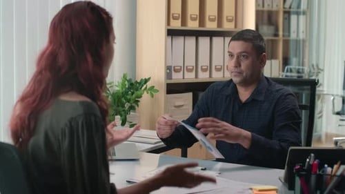 Man and Woman Discussing Data in Modern Office