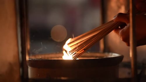 Lighting Incense Sticks at a Temple at Night