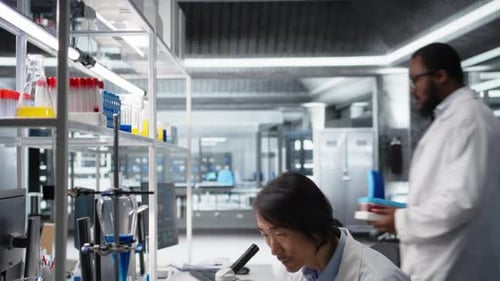 Scientists Work in Modern Lab with Microscope