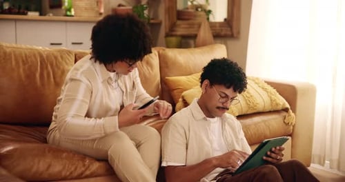 Couple Relaxing at Home Using Phone and Tablet