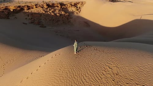 Wonderfull shot with drone at sunset on man, walking and in the desert dunes of morocco.