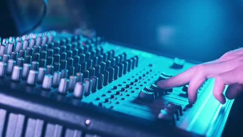 Hand Settings Volume Level Controls on Mixing Console Faders Neon Light CloseUp