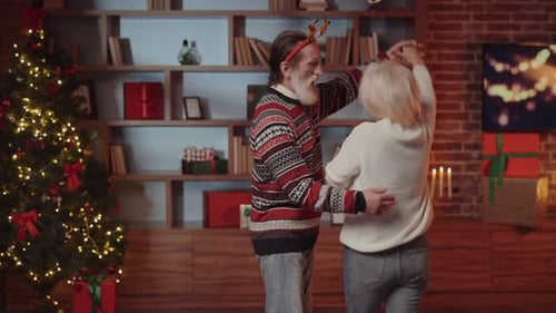 Senior Couple Dancing at Christmas by Tree at Home