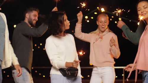 Friends Dancing with Sparklers at Outdoor Evening Celebration